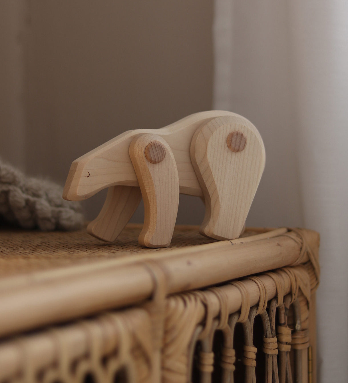 A white Tobe wooden polar bear toy available at Babipur displayed on a rattan drawer. This polar bear figure has movable joints. A range of Tobe animals are available at Babipur. 