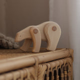 A white Tobe wooden polar bear toy available at Babipur displayed on a rattan drawer. This polar bear figure has movable joints. A range of Tobe animals are available at Babipur. 