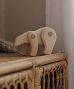 A white Tobe wooden polar bear toy available at Babipur displayed on a rattan drawer. This polar bear figure has movable joints. A range of Tobe animals are available at Babipur. 