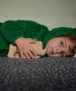 A child playing with the natural unpainted Tobe wooden rhinoceros toy available at Babipur 