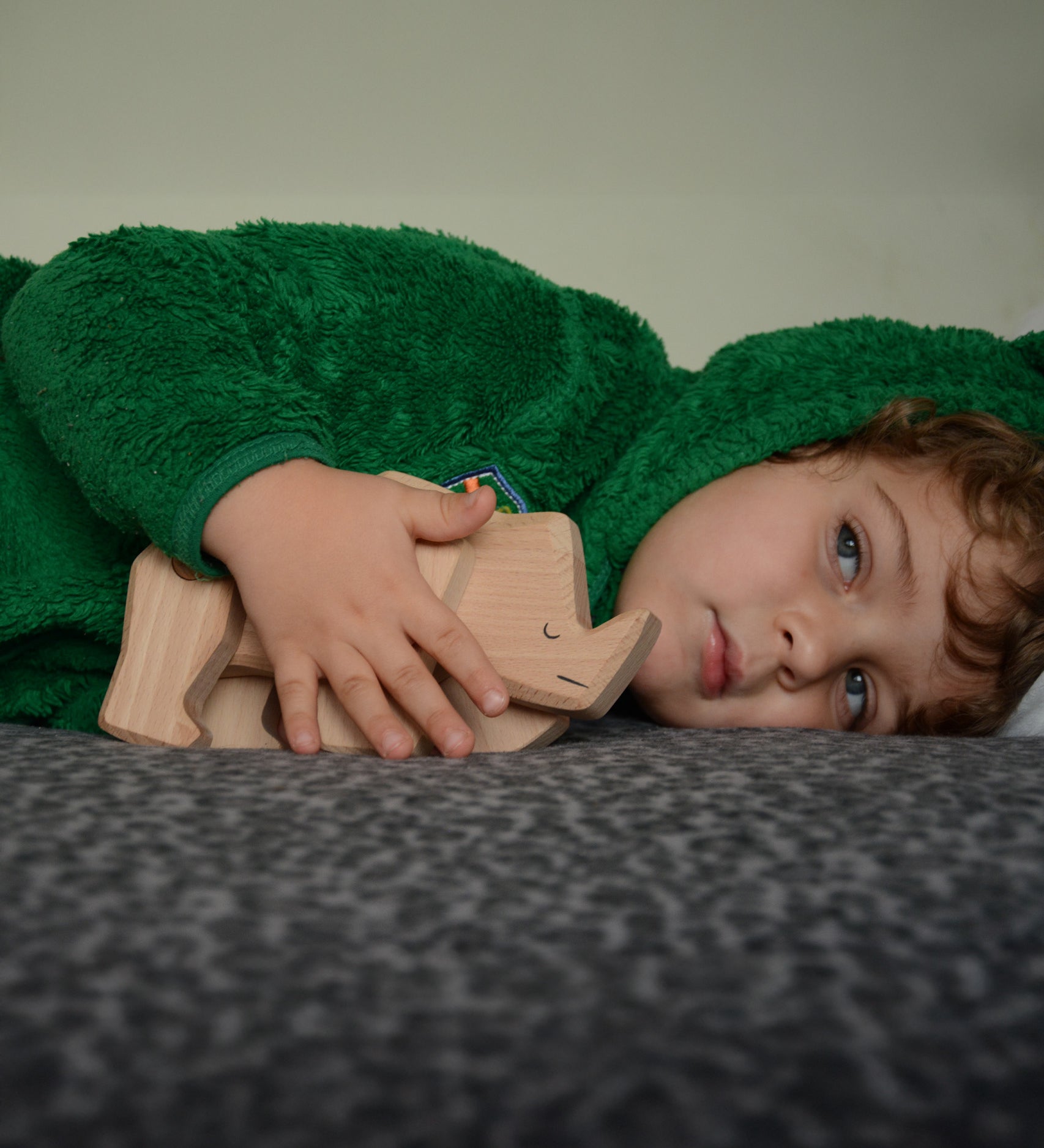 A child playing with the natural unpainted Tobe wooden rhinoceros toy available at Babipur 