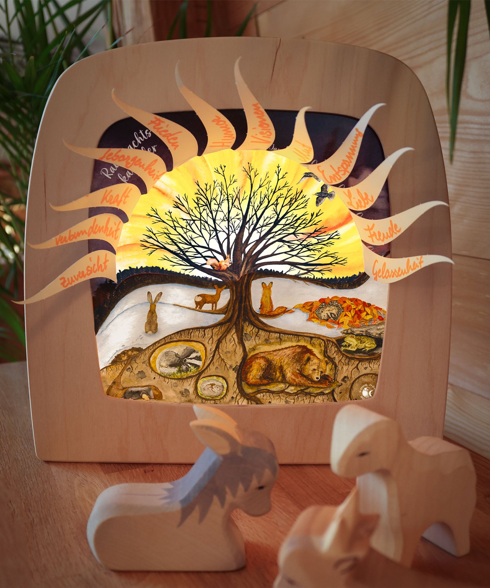 A cosy festive display with the Toverlux 12 holy nights sonne mond und erde silhouette inside a lamp. Silhouette features each date with a cut out for a message. Silhouette and lamp available at Babipur