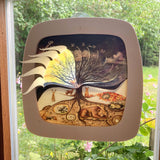 The Toverlux 12 holy nights sonne mond und erde silhouette inside a magic frame on a window showing the cut outs for each date folded out. Silhouette and frame are both available at Babipur
