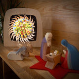 Mary and Joseph with baby Jesus and some animal wooden figures next to the Toverlux sonne mond und erde nativity advent calendar available at Babipur. Calendar has all of the windows open revealing a lit up silhouette. 