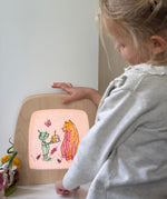 A child looking at the Toverlux wooden frame and a silhouette from the colouring  book by Daniela Dreschers available at Babipur.
