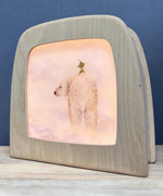 An illustration of a gnome sitting on the back of a polar bear from the Garden Adventures Of Griswald Gnome Toverlux StoryLux Silhouette Sets, by Daniela Drescher. The illustration is inside a Magic Lamp which is stood on a table