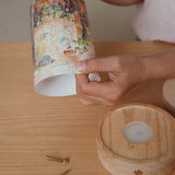 An adult holding a Eentje Van Margo light wish illustration ready to put on the Toverlux rechargeable lantern. Illustration is held by two split pins. Lantern and illustration both available at Babipur. 
