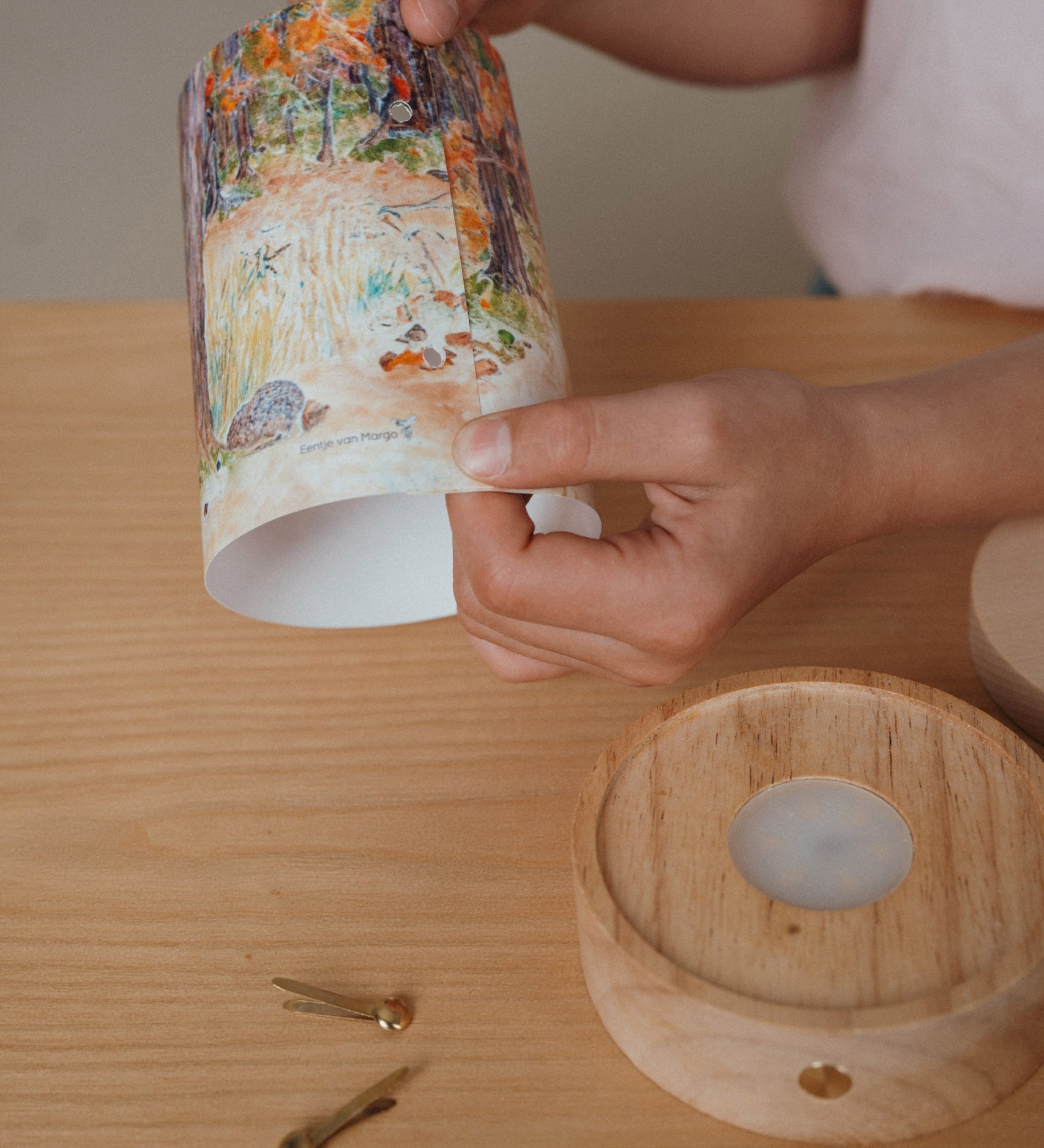 An adult holding a Eentje Van Margo light wish illustration ready to put on the Toverlux rechargeable lantern. Illustration is held by two split pins. Lantern and illustration both available at Babipur. 