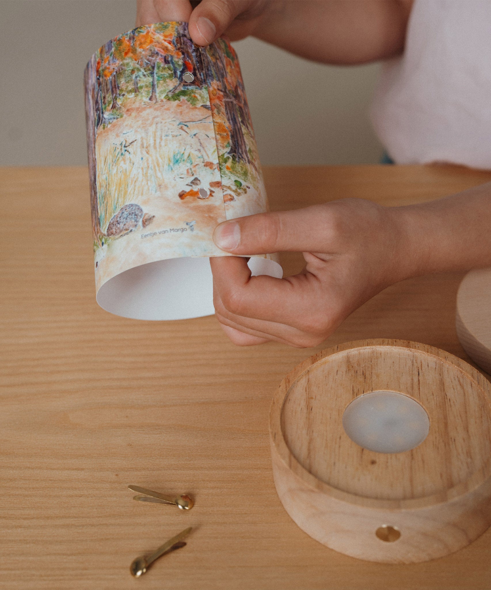 An adult holding a Eentje Van Margo light wish illustration ready to put on the Toverlux rechargeable lantern. Illustration is held by two split pins. Lantern and illustration both available at Babipur. 