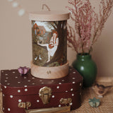 A retro cosy inspired display including the Toverlux rechargeable lantern on top of a mini suitcase with a Robin Pieterse light wish illustration inserted the lantern. Both the illustration and lantern are available at Babipur.