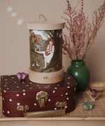 A retro cosy inspired display including the Toverlux rechargeable lantern on top of a mini suitcase with a Robin Pieterse light wish illustration inserted the lantern. Both the illustration and lantern are available at Babipur.
