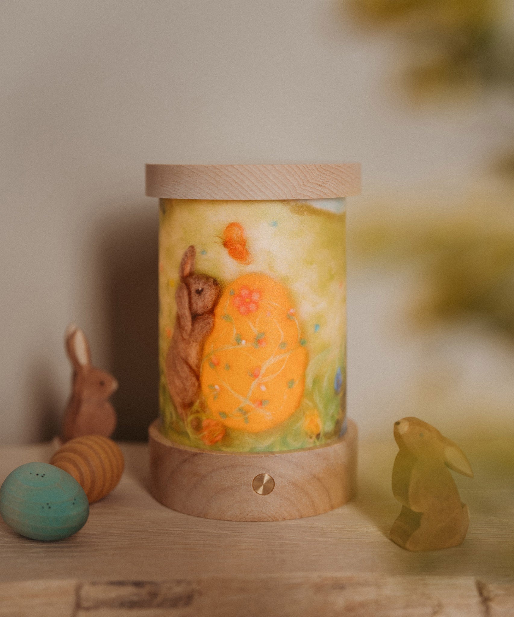 A retro Spring inspired display with Ostheimer rabbits and eggs. The Toverlux rechargeable lantern is on a wooden surface with a light wish illustration inserted the lantern. Both the illustration and lantern are available at Babipur.