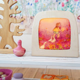 Toverlux Little goose silhouette inside a wooden magic lamb next to various wooden toys on a white shelf in the Babipur playroom. 