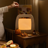 Hand holding an autumn silhouette for the Toverlux Magic Lamp by Het Wol Feetje in bedroom setting.