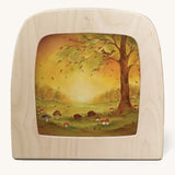 A Toverlux silhouette in the magic lamp with a Autumn leaves silhouette inside by Baukje Exler available at Babipur. A pastel illustration of hedgehogs near mushroom and under a tree with falling autumn leaves