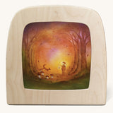 A Toverlux silhouette in the magic lamp with a Autumn light silhouette inside by Baukje Exler available at Babipur. A pastel illustration of a small child walking though Autumn woodland with a glowing torch