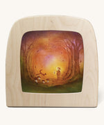 A Toverlux silhouette in the magic lamp with a Autumn light silhouette inside by Baukje Exler available at Babipur. A pastel illustration of a small child walking though Autumn woodland with a glowing torch