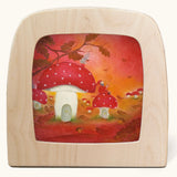 A Toverlux silhouette in the magic lamp with red autumn  artwork by Baukje Exler. An illustration of little toadstool houses.