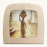 Toverlux morning light silhouette by Berit Strasser a oil pastel style of a woman holding a basket on her head. Shows silhouette in a wooden frame