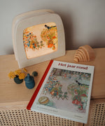 A cosy display with the Toverlux August silhouette in a wooden lantern by Elsa Beskow standing on a wooden surface next to a Grimms rainbow and Grapat cup available at Babipur.