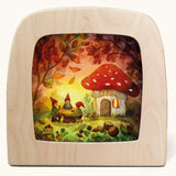 Toverlux magic lamp with a Autumn gnome toadstool picnic silhouette by artist Vogel Geluk. A watercolour style illustration of a toadstool house in a forest with a table with three gnomes sat around it. A range of Toverlux silhouettes, lamps and accessories are available at Babipur. 