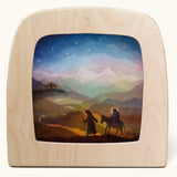Toverlux magic lamp with a starry night pilgrimage silhouette by artist Vogel Geluk. A watercolour style illustration of Mary, Joseph and teh donkey traveling along a path under a starry sky. A range of Toverlux silhouettes, lamps and accessories are available at Babipur. 
