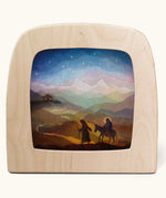 Toverlux magic lamp with a starry night pilgrimage silhouette by artist Vogel Geluk. A watercolour style illustration of Mary, Joseph and teh donkey traveling along a path under a starry sky. A range of Toverlux silhouettes, lamps and accessories are available at Babipur. 