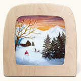 Toverlux magic lamp with a Winter sled song silhouette by artist Vogel Geluk. A watercolour style illustration of a snow covered Winter scene. There is a snowman and children on a sled in the background along with a cosy cottage in the distance. A range of Toverlux silhouettes, lamps and accessories are available at Babipur. 