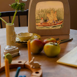 Toverlux Magic Lamp on table displaying artwork by Elsa Beskow, Peter in blueberry land, kids on a boat with a leaf sail.