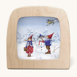 A Toverlux silhouette from artist Daniella Drescher, compatible with the Magic Lamp or Magic Frame both available at Babipur. Silhouette is showing a illustration of a winter scene with 2 people standing next to a snowman