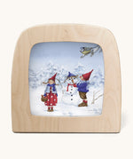 A Toverlux silhouette from artist Daniella Drescher, compatible with the Magic Lamp or Magic Frame both available at Babipur. Silhouette is showing a illustration of a winter scene with 2 people standing next to a snowman