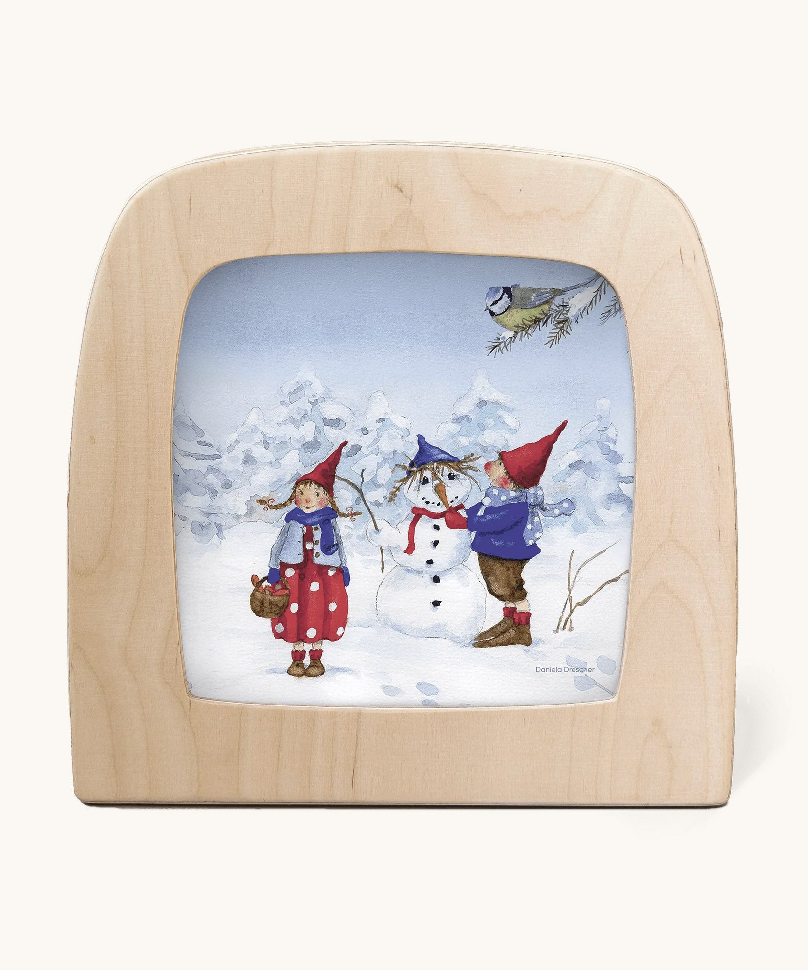 A Toverlux silhouette from artist Daniella Drescher, compatible with the Magic Lamp or Magic Frame both available at Babipur. Silhouette is showing a illustration of a winter scene with 2 people standing next to a snowman