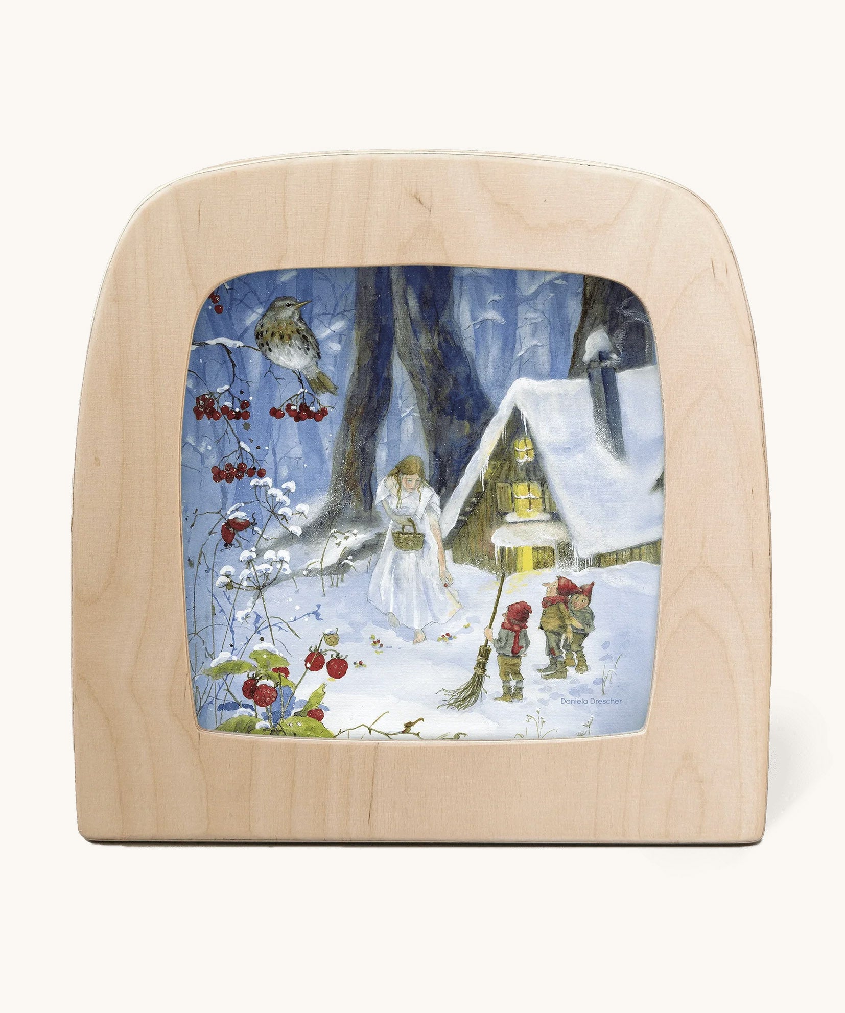 A Toverlux silhouette from artist Daniella Drescher, compatible with the Magic Lamp or Magic Frame both available at Babipur. Silhouette is showing a illustration of a winter woodland scene with gnomes standing next to a cabin with a woman dressed in white