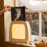 Hand placing a Toverlux Tijana Draws Whale silhouette into a Toverlux Magic Lamp Night Light Box on a windowsill.