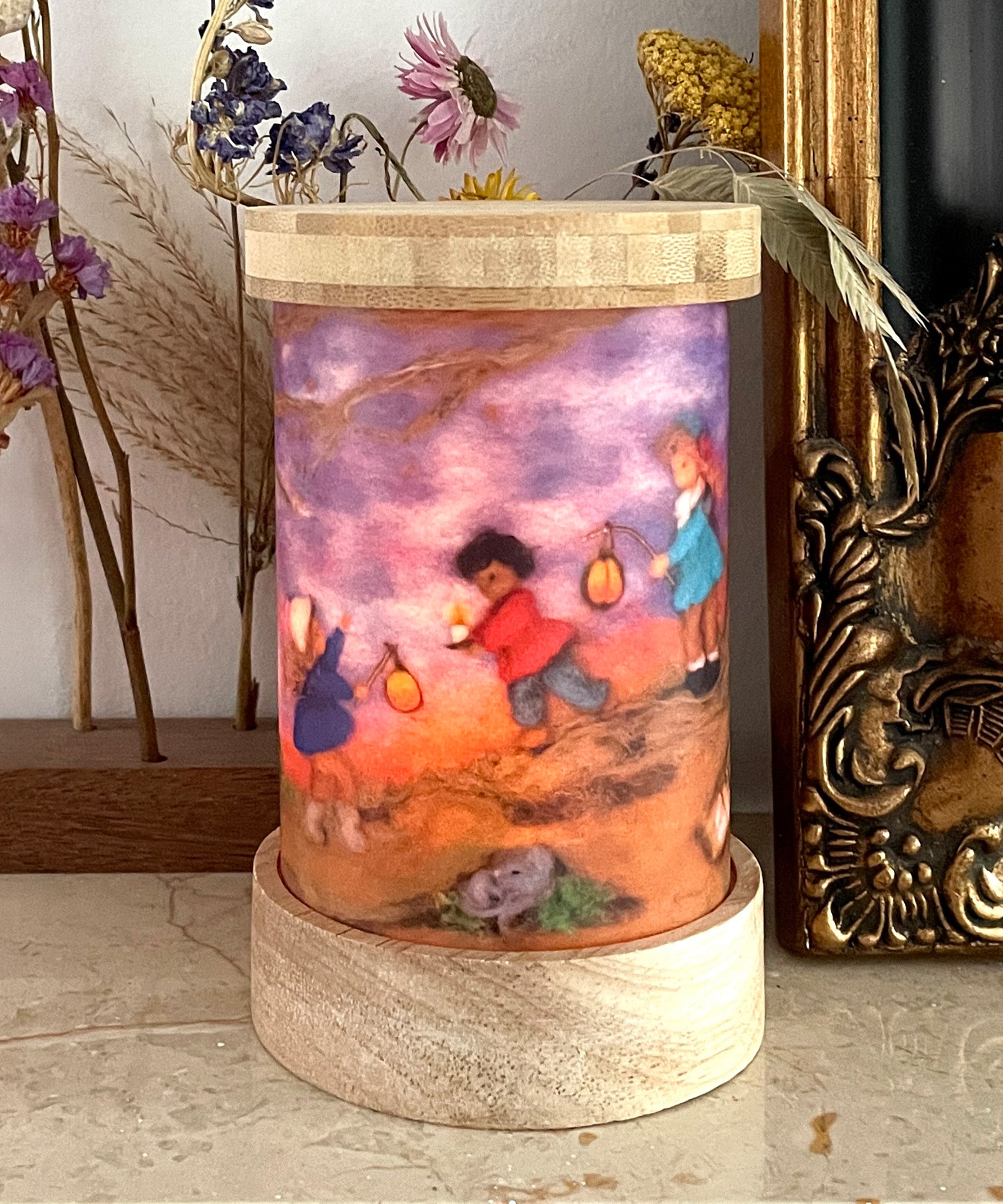 A beautiful illustration of Lantern Walk by Het Wol Feetje, inside a Toverlux Magic Lantern with flowers and a bronze coloured picture frame in the background