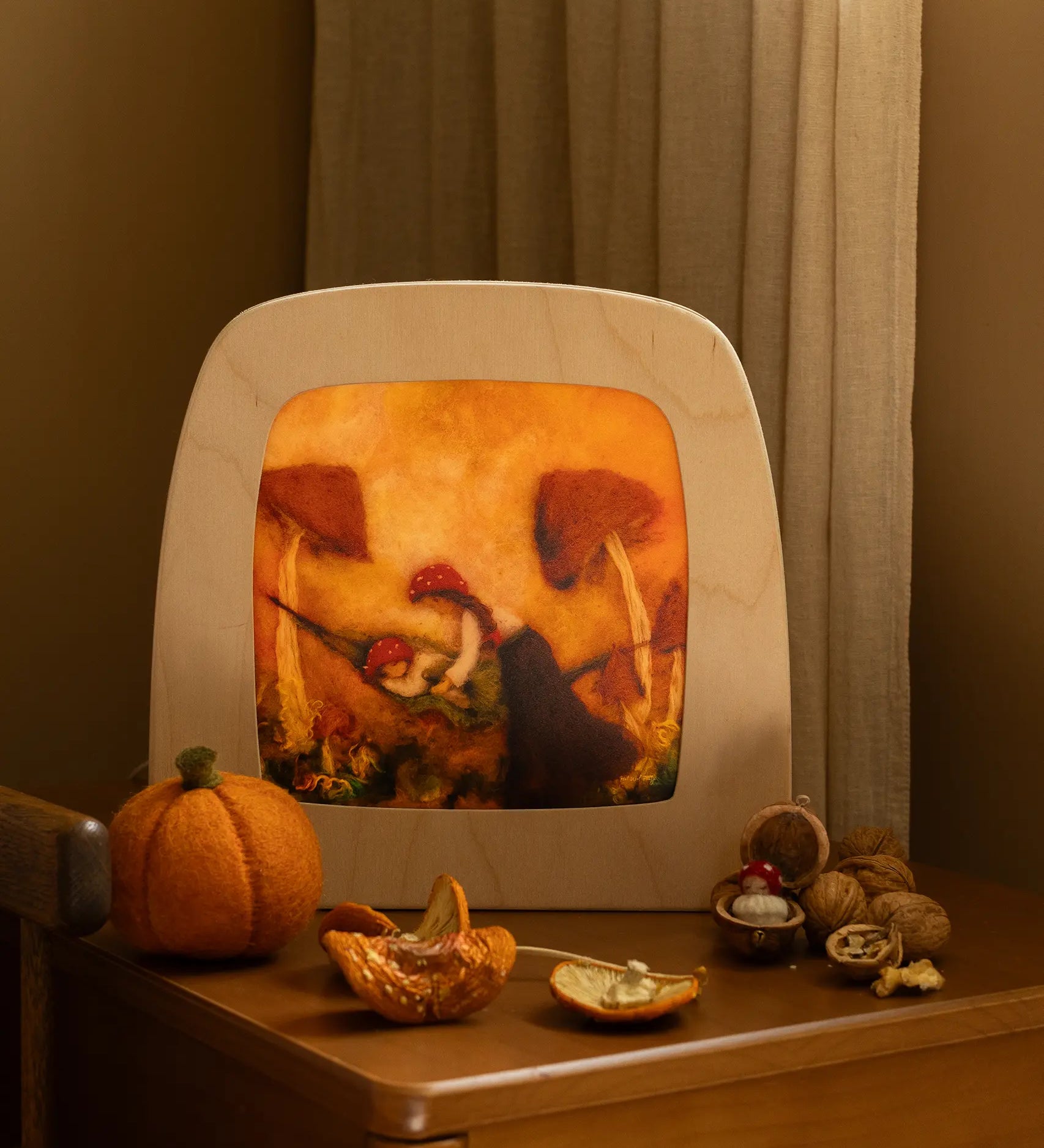 Toverlux Magic Lamp with autumn toadstool artwork by Het Wol Feetje on bedside table with walnuts.