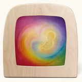 A Toverlux silhouette in the magic lamp with baby in womb rainbow artwork by Baukje Exler. A pastel illustration of a baby in a womb with a dreamy rainbow background.