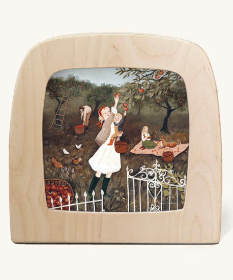 Orchard morning Toverlux Magic Lamp silhouette inside a wooden magic lamp. Artwork By Robin-Pieterse. A delicate painting style illustration of a woman and a child picking apples from a tree with a girl and a dog on a blanket in the background. This silhouette is available at Babipur