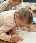 A child colouring a page from the Toverlux story colouring book available at Babipur.