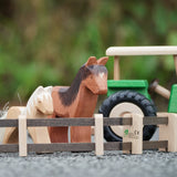 Beck Holzspielzeug wooden toy farm fences in small-world play setup with Ostheimer farm animal toys and a wooden tractor in the background.