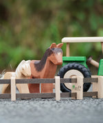 Beck Holzspielzeug wooden toy farm fences in small-world play setup with Ostheimer farm animal toys and a wooden tractor in the background.