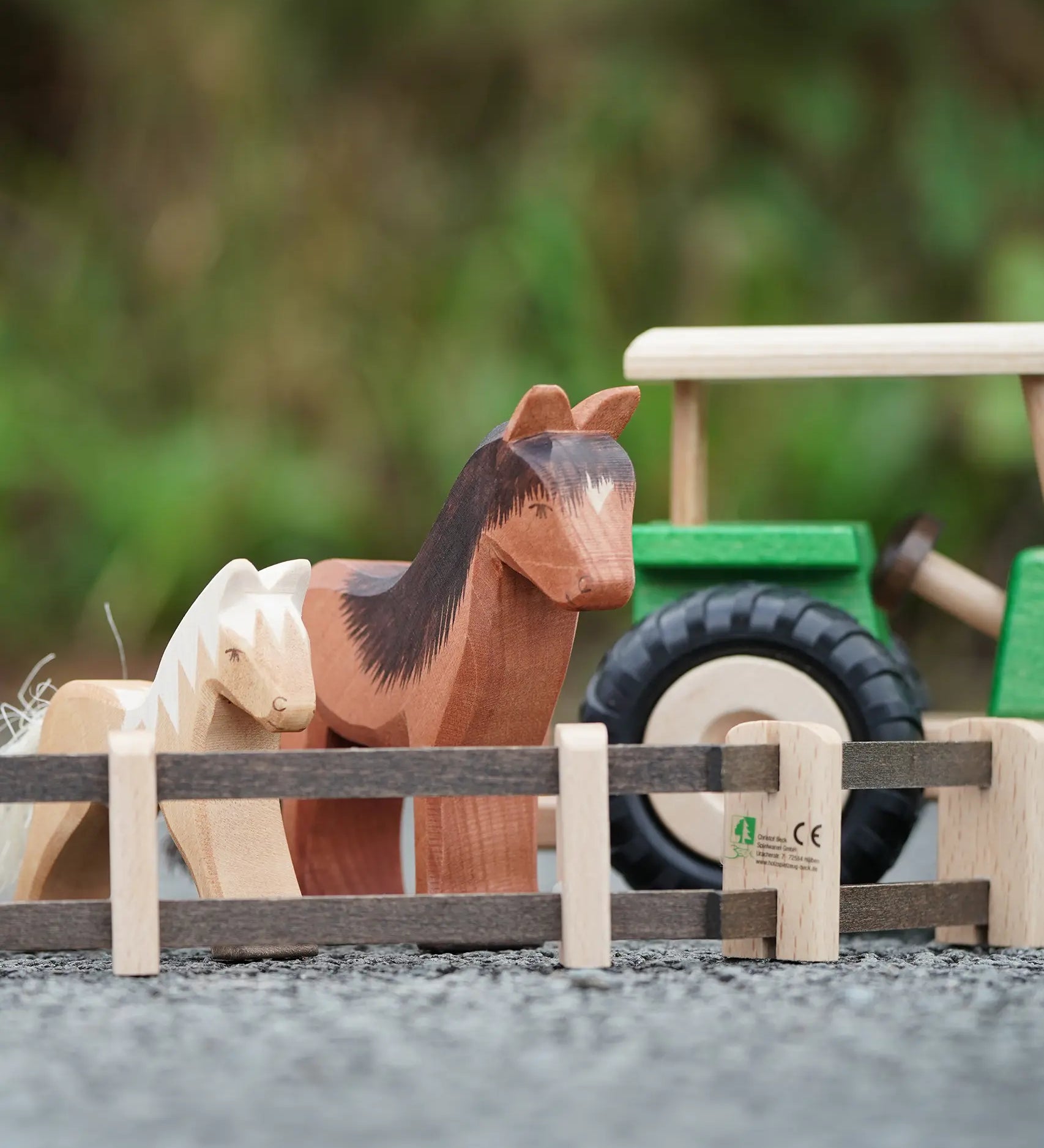 Beck Holzspielzeug wooden toy farm fences in small-world play setup with Ostheimer farm animal toys and a wooden tractor in the background.