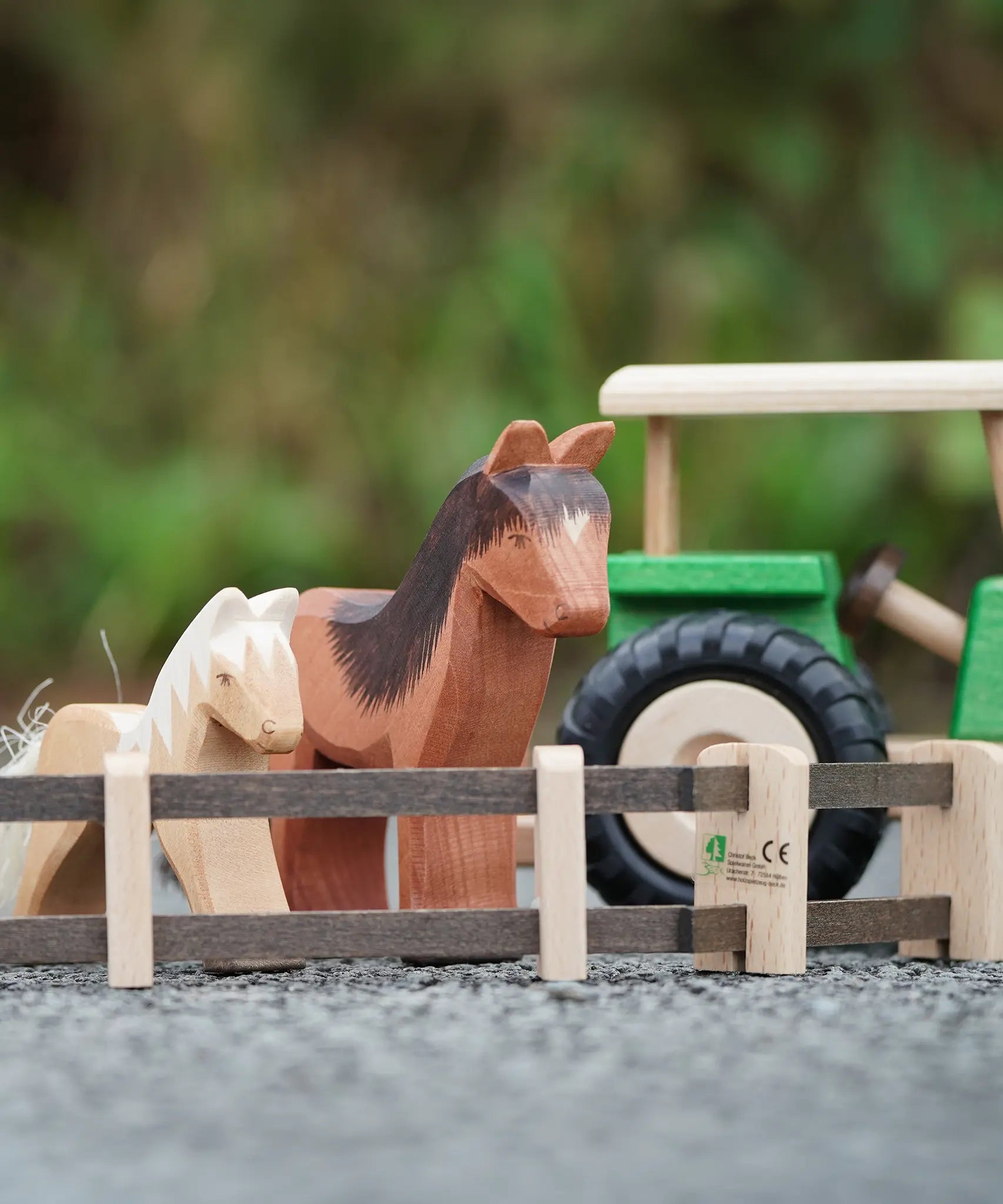 Beck Holzspielzeug wooden toy farm fences in small-world play setup with Ostheimer farm animal toys and a wooden tractor in the background.