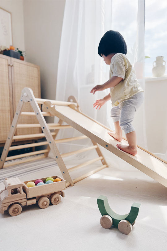 Child playing on a wooden Triclimb Pikler Style Triangle with Miri Side to represent Triclimb toys at Babipur, official UK stockist.