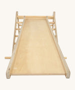 Triclimb wooden Miri slide attached to a natural Triclimb wooden pikler climbing frame showing the smooth side of the slide that can be used as a ramp or slide.