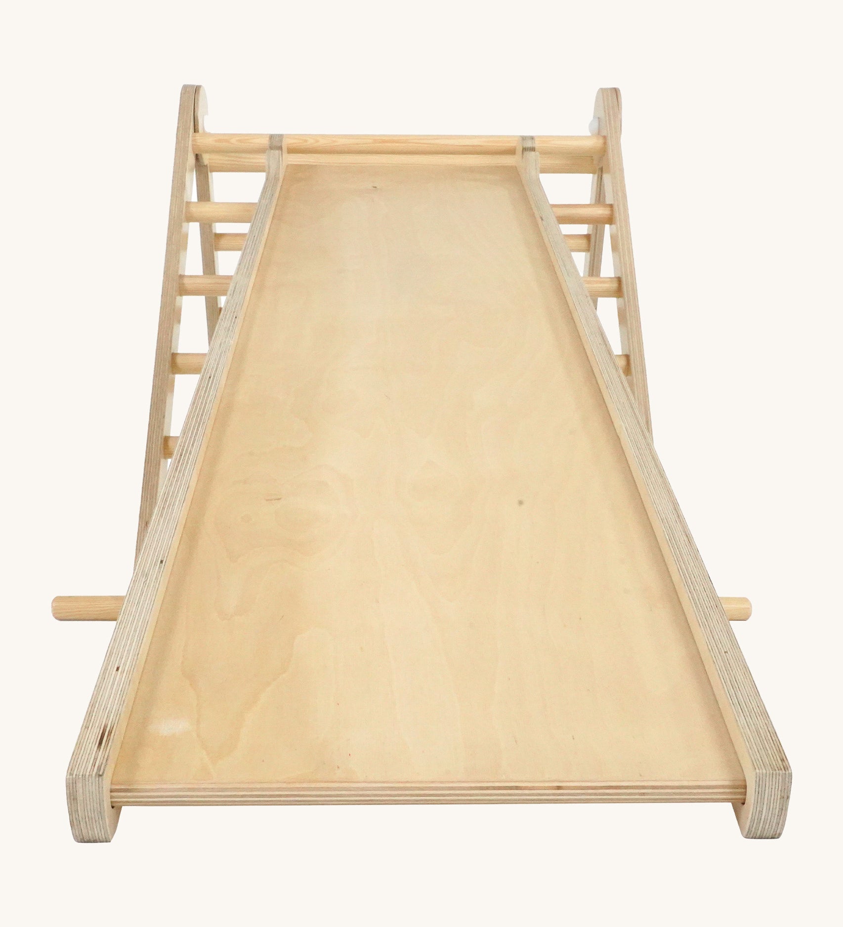 Triclimb wooden Miri slide attached to a natural Triclimb wooden pikler climbing frame showing the smooth side of the slide that can be used as a ramp or slide.
