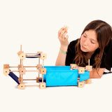 A boat made from the Trigonos wooden medium construction kit with a child holding a piece above the build