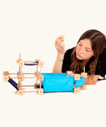 A boat made from the Trigonos wooden medium construction kit with a child holding a piece above the build