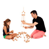 Father and daughter building a tower A using various wooden poles and blocks from the Trigonos mini large construction set