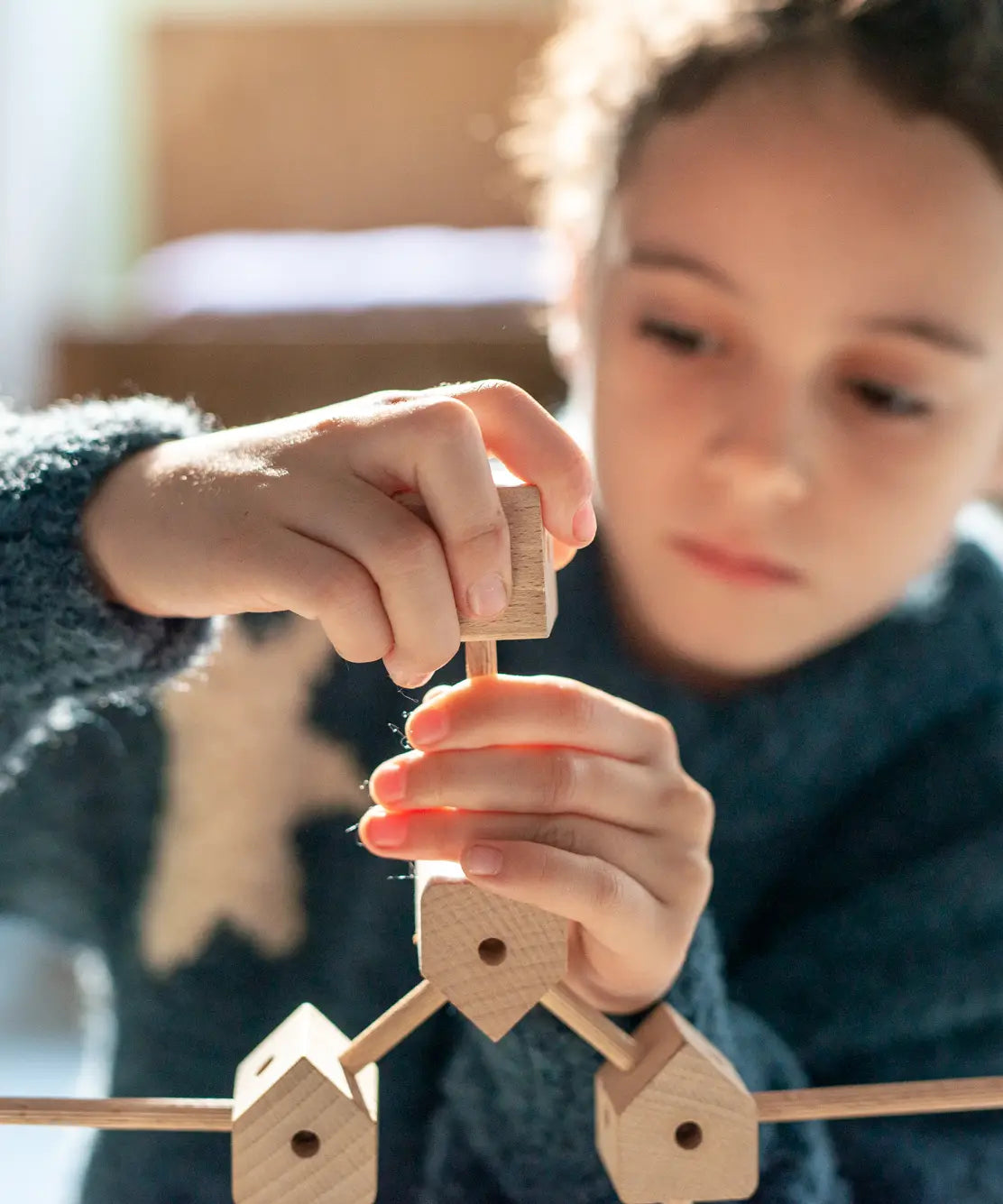 Child assembling various wooden poles and blocks out of the Trigonos mini large construction set 